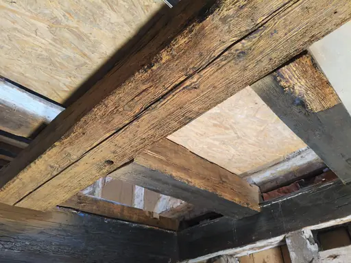 Deckenbalken in der Klingenmühle Welzheim nach dem Trockeneisstrahlen, rechts noch die schwarze Farbe